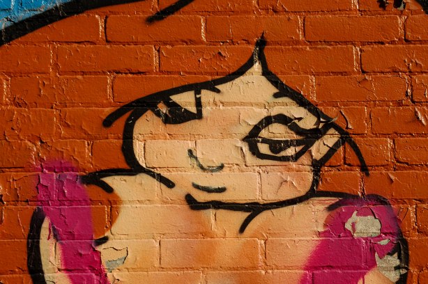 Graffiti painting of a topless woman from the waist up, long light brown hair, 