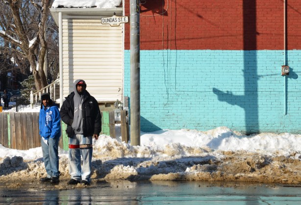 Two men standing on the corner in the slush and snow. 