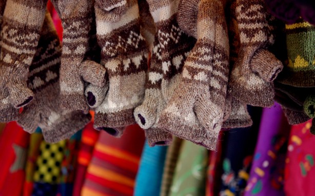 warm woolly mitts for cold days.  In the foreground are brown and beige patterned fingerless mitts.  In the background are multicoloured mitts, some striped and some with geometric patterns.