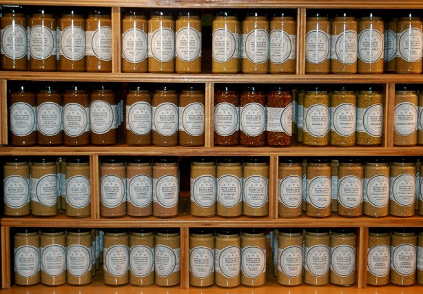 many varieties of Koslicks mustard in a display.  Jars of the different kinds are grouped together.