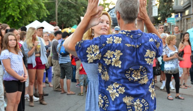 a couple dancing in the street with the crowd behind them