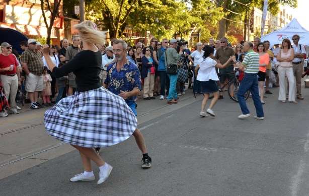 two couples dancing in the street while a group of people watch