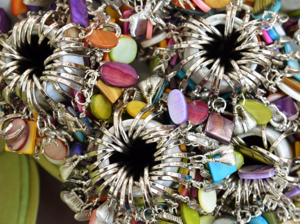 Piles of bookmarks made from metal and colourful stones that have been organized in containers.