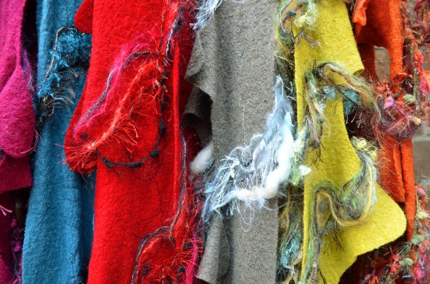 pieces of felt in blue, red, grey and yellow hanging in a vendor's stall at an arts and crafts fair