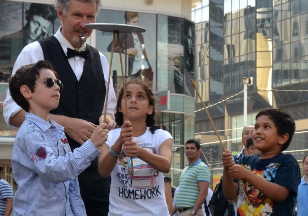 3 kids passing a spinning plate from one to the next using sticks