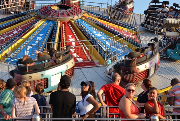 Some people in a line up waiting to get on a ride, the Twister ride is in the background