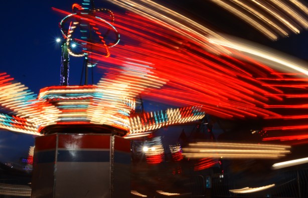 blurred lights in red, white and blue, as one of the rides spins around