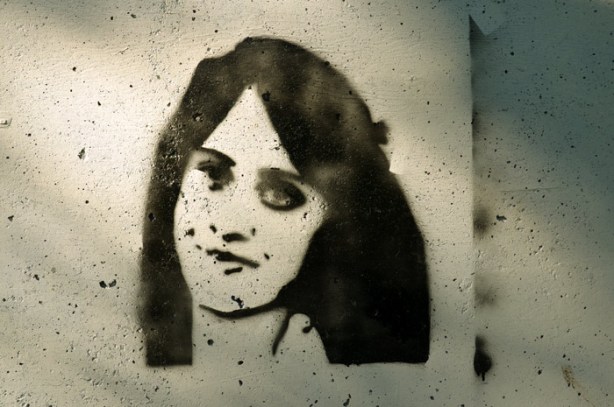 a stencil graffiti in black and white of a woman's face.