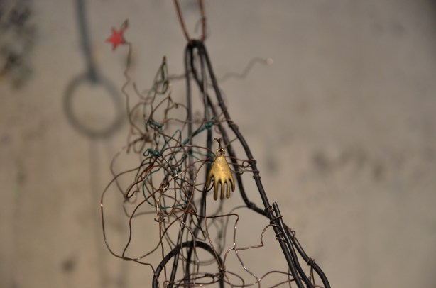 part of a wire sculpture showing a little gold trinket in the shape of a hand