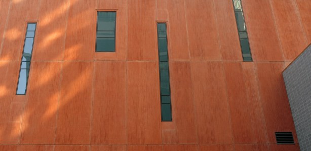 the side of a brown building,  There are four long skinny windows. 