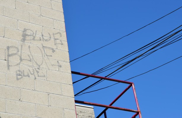 Concrete block wall with the words blue, blue, blue written on it.  The sky behind is very blue.