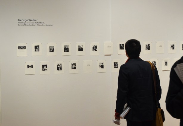 A man looking at a series of small black & white prints in an art gallery
