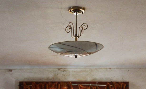 old brass ceiling lamp is hanging from a grubby ceililng.  There is a crack in the ceiling.  