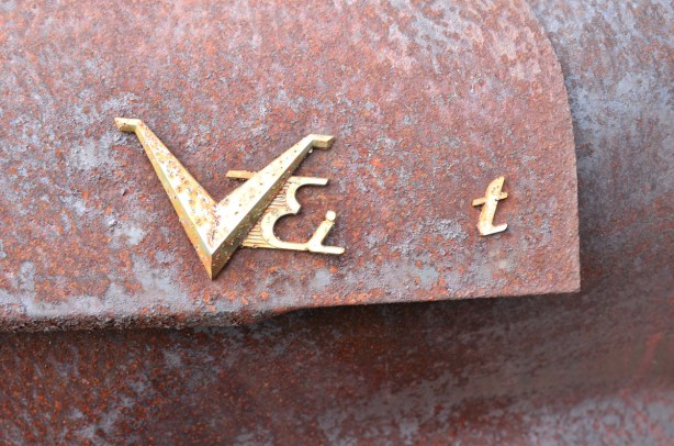 a broken logo with a metal Vei on a very rusty car, close up photo