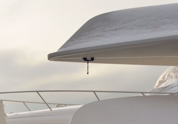 The bows of two white boats, one on top of the other.  The sun is trying to break through the clouds in the background of the picture, making for interesting lighting conditions.