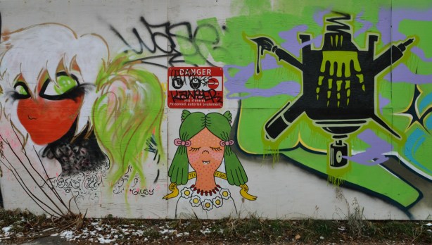 Graffiti of two women's heads. There is also a red and white danger sign in the middle of the picture. 