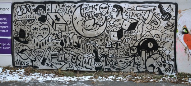 Silver and black graffiti that consists of drawings many different things - skull, bottles, hearts, hats, moon, dice, etc. as well as some words, slayed, the truth is out there, and danger