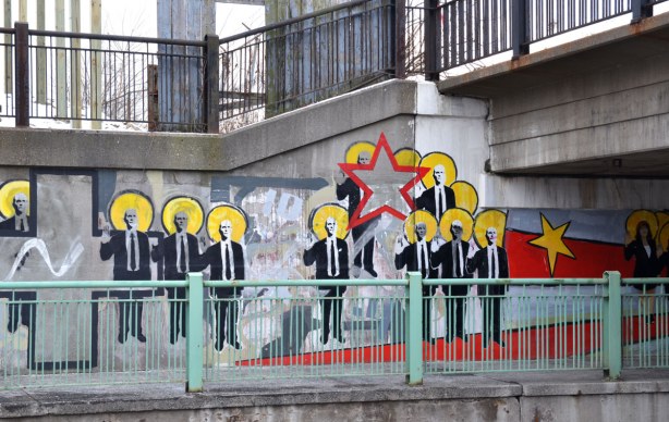 part of the mural showing many men in suits, a yellow star and a red star. 