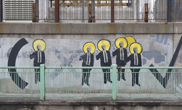 men in suits forming part of a mathematical equation. A multiplication sign and part of a long division sign. 