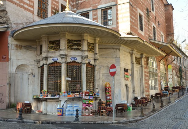 A corner store in an old stone and brick building.  The front is rounded and has a few large windows.  