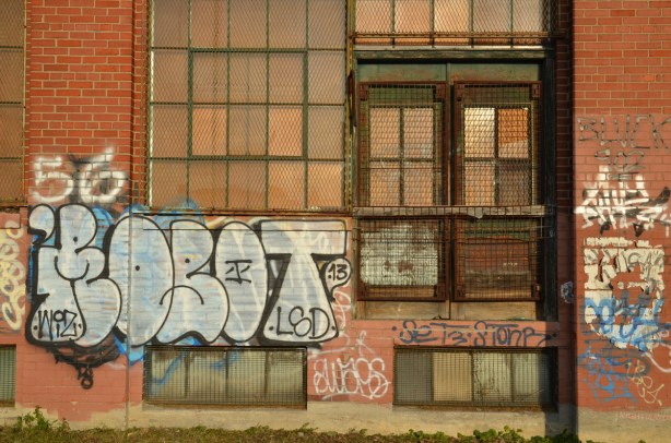 Large windows on a red brick building. The window frames are metal and they are rusty.