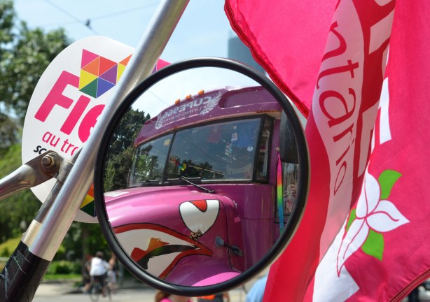 Reflection in the round side view mirror of an old school bus that has been painted pink by CUPE.  