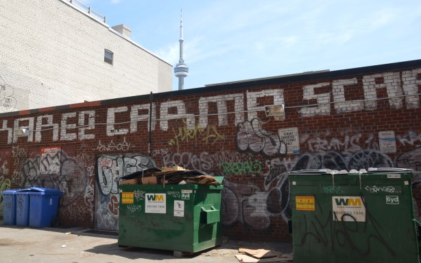 graffiti on a brick wall on Bulwer St., with the CN tower behind in the distance