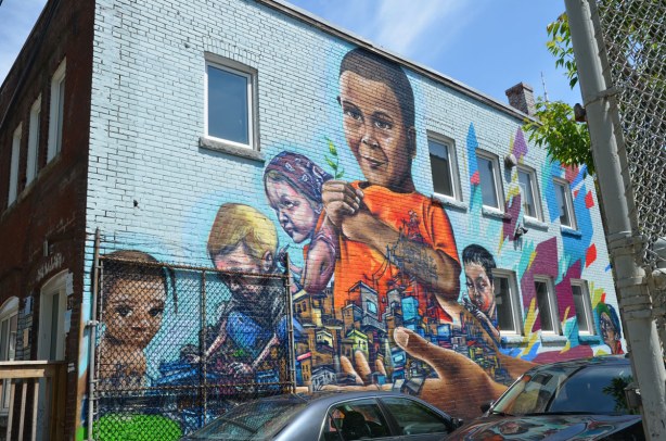 graffiti on a brick wall on Bulwer St., children including a larger than life sized boy wearing an orange T-shirt