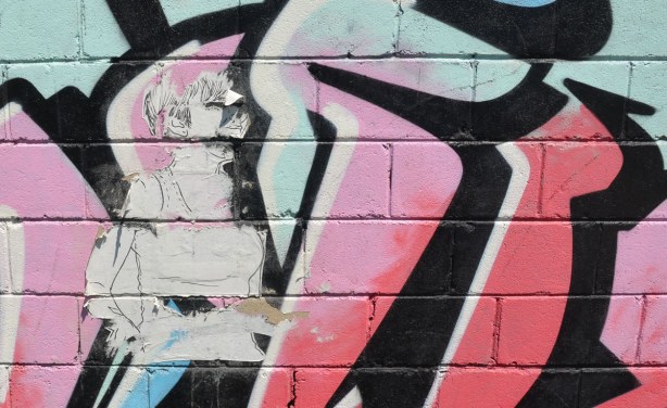 large paper stencil of the top part of a woman is still there although parts of it have worn away