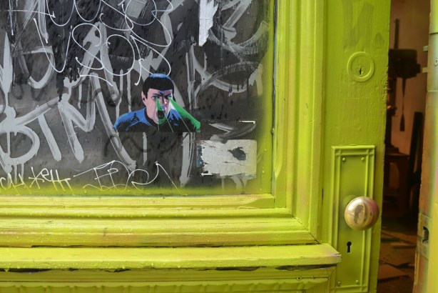 little people graffiti, sticker of Dr. Spock from Star Trek on the window in a door that has been painted a bright yellowish green colour