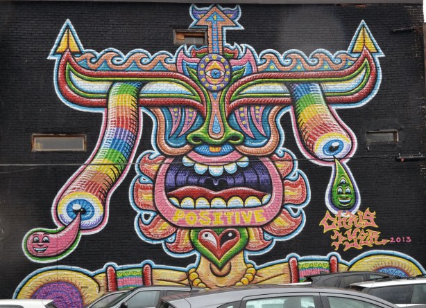 multicoloured abstracted face with head piece.  mouth wide open showing tongue and teeth