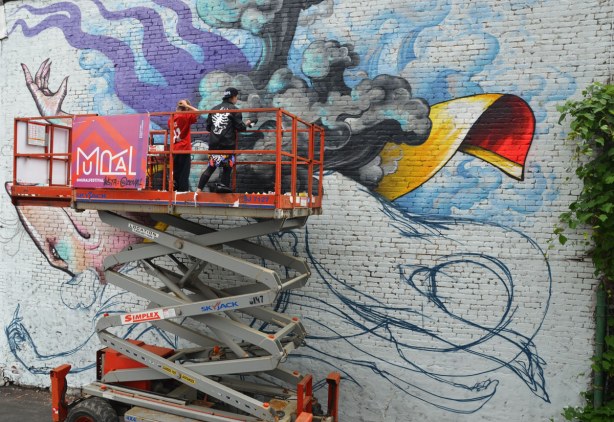 mural painted on the side of a building in Montreal in the process of being painted.  A rat is lying on its back