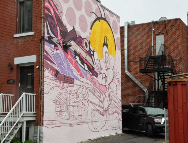 large mural on the side of a two storey building in Montreal.  A partially finished painting of the cartoon character tweety bird. 