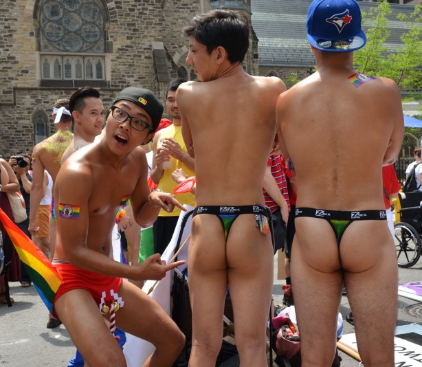 One guy in red underpants (with Christmas bells attached to the front) is pointing to the bare bottoms of his two male friends.  He is making an exaggerated facial expression of surprise and shock. 