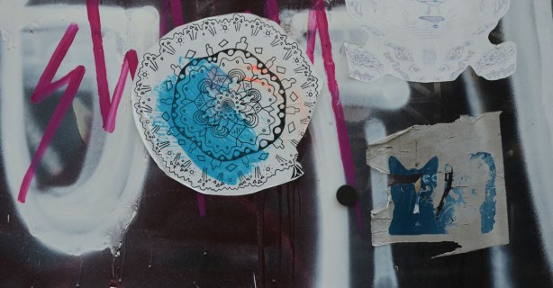 two stickers on a wall.  One is the head of a blue cat.  The other is a lacey looking circular design. 