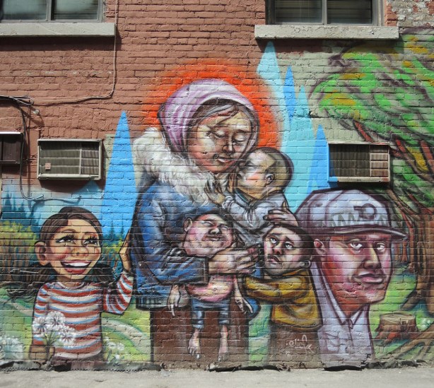 A woman is holding an infant and a small child. Another child is clinging to her. A man is to her right and a girl is to her left. The infant is ugly and may not really be an infant but instead be a little roly poly old man... or a hybrid of the two
