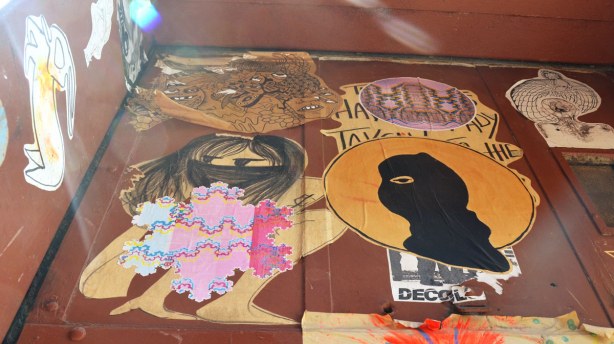 An assortment of some of the stickers.  These are the ones that were on the top part of the window.  A person  wearing a balaclava, a black haired girl with the lower part of her face covered in black, an outline drawing of a rabbit, 