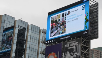 A large electronic billboard high above Yonge St. A picture of one of my buskerfest tweets is being displayed.