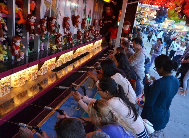 A number of people are competing to win a stuffed monkey.  They are shooting water into a target. 