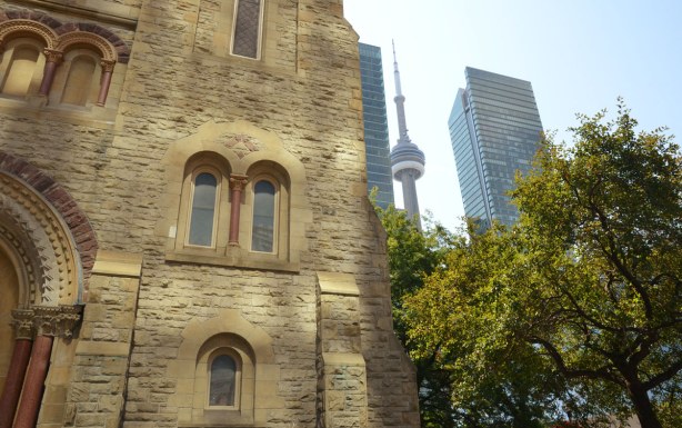 Part of the stone church, St. Andrews Presbyterian, dominates the photo. Part of a tree, the edge of a skyscraper and the CN Tower are on the right side of the photo.