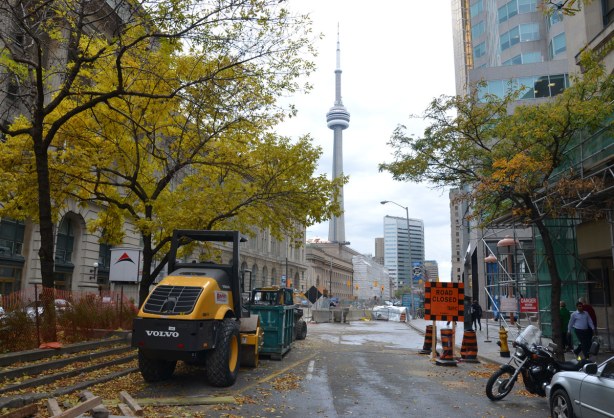 looking west on Front St. towards Union Station.  Construction equipment is in the foreground of the photo.  The CN tower is in the background. 