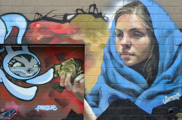 mural on a wall of a young woman with a large blue scarf handing money to a cartoon rabbit 