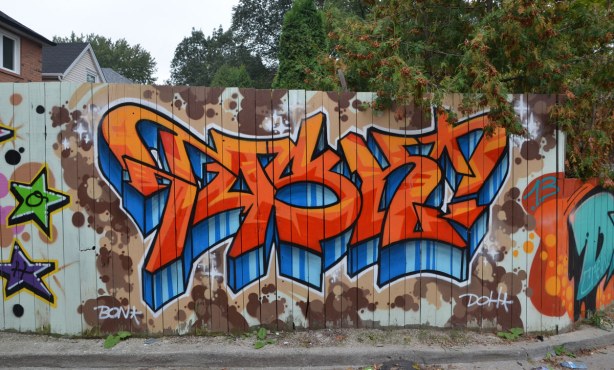 Large bright orange and blue tag on a wood fence