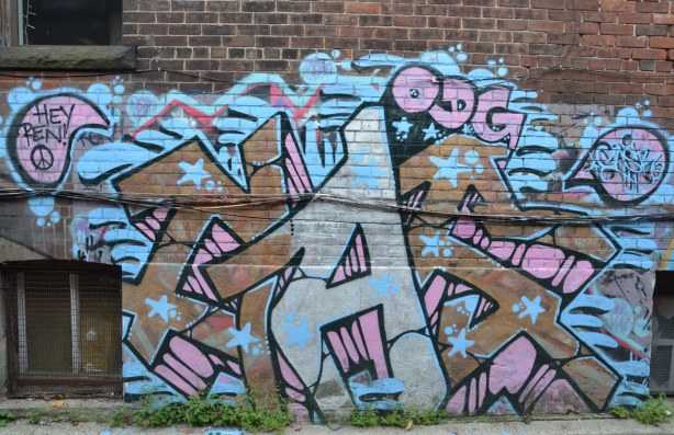 pink, brown, and light blue tag on a wall. 