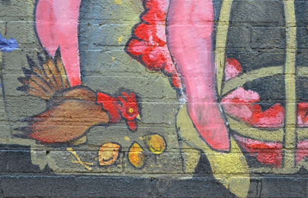 detail from mural - chicken pecking at some nuts (corn?) on the ground beside legs wearing yellow high heel shoes
