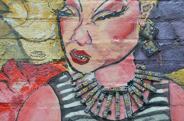 detail from mural - close up of woman with black and white striped top, glittering neacklace and ear rings