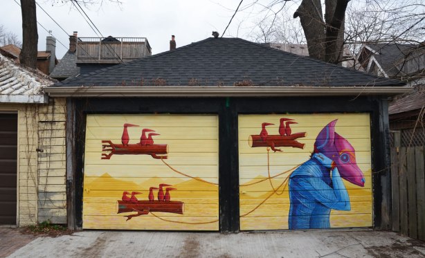 street art mural on a double garage. yellow background. three floating logs with birds sitting on them are being pulled by a creature with a pink and purple head as well as a blue body.