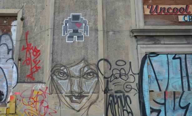 lovebot and an anser black, white and grey face on a conrete wall. 