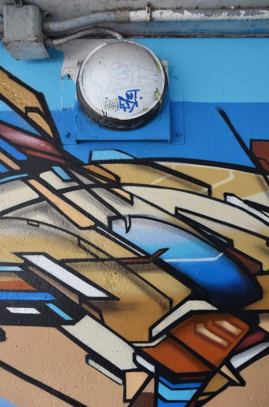 Street art in blues and browns under a railway bridge