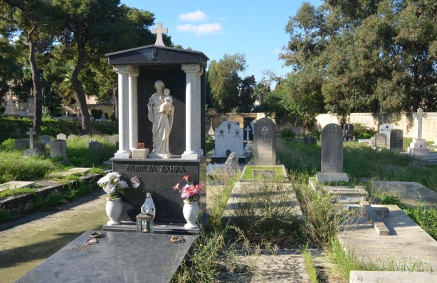 tombstones in a cemetery. Memorial statue under an arched portico.